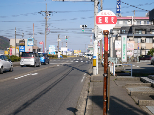  バス停「飯塚町」で降りて「西学園・飯塚」の交差点を右に曲がってください。